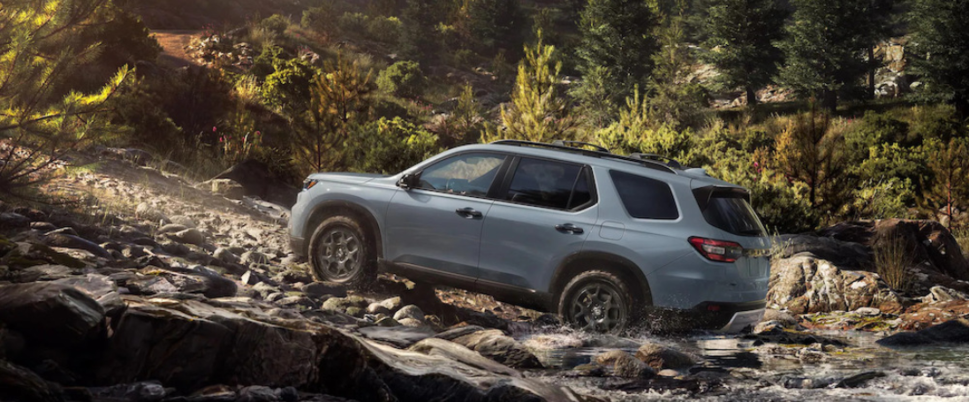 A gray 2025 Honda Pilot SUV driving up a steep riverbank