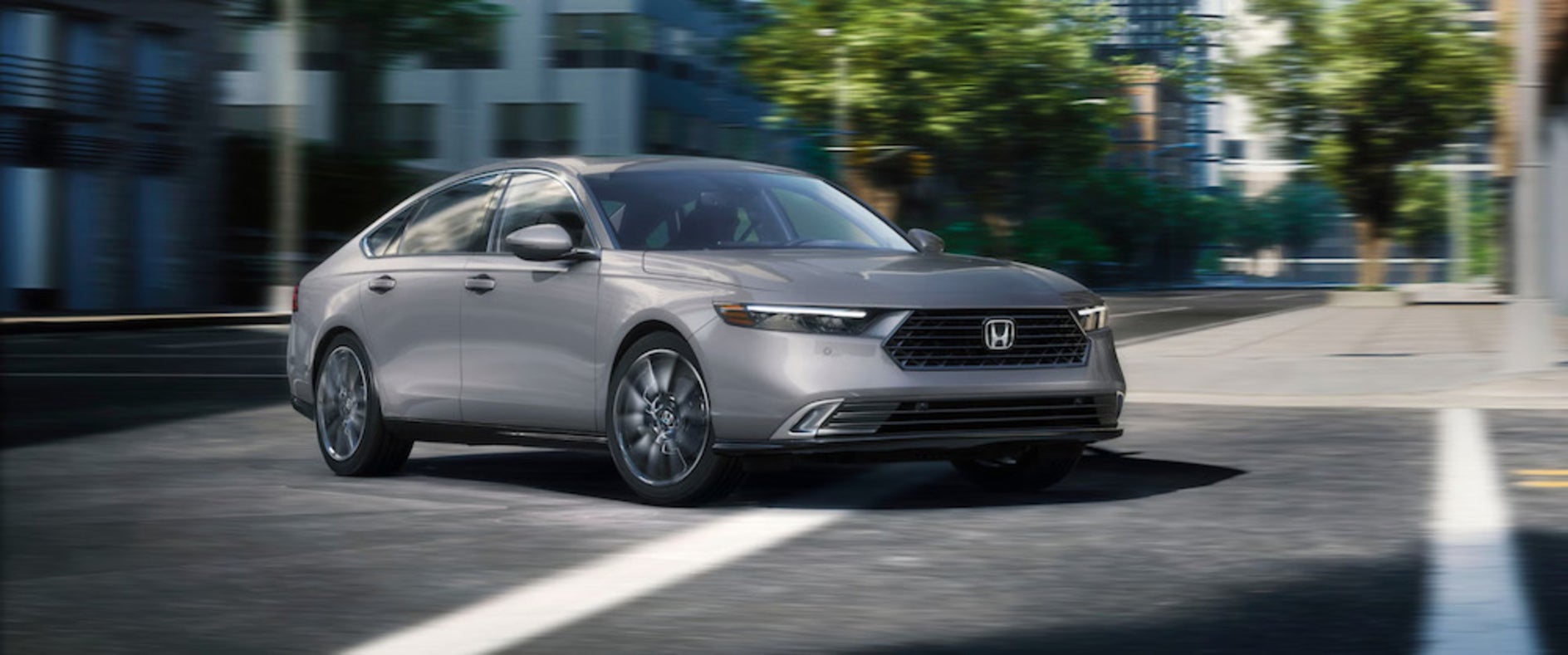 A gray Honda Accord sedan turning a corner on a city street