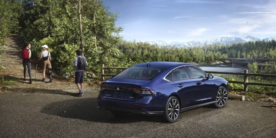 Hikers walking away from a blue 2026 Honda Accord parked on a mountain overlook