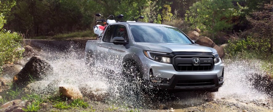 A gray 2026 Honda Ridgeline truck driving through a stream bed