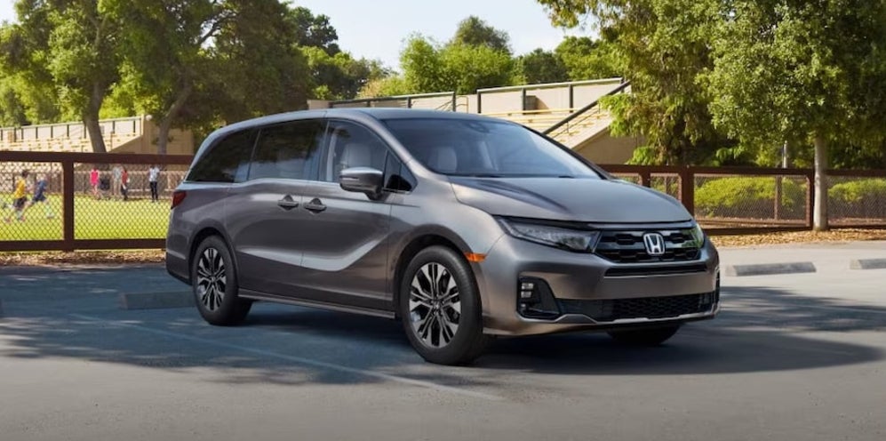 A gray 2026 Honda Odyssey minivan parked outside an athletic field